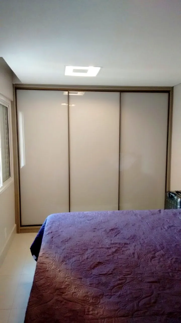 Guarda-roupa planejado com portas de correr e perfil amadeirado, em quarto de casal em Brasília